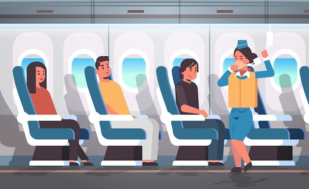 緊急時の現代の飛行機のボードインテリアで酸素マスクを使用する方法を示す乗客の客室乗務員のためのライフベスト付き安全指示を説明するスチュワーデス プレミアムベクター