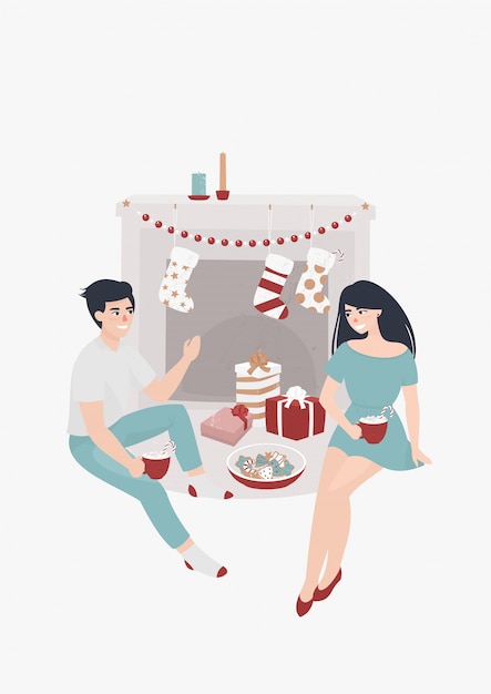 Young couple sits by the fireplace and drinks cocoa surrounded by christmas presents Premium Vector