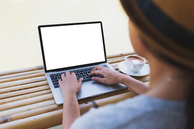 Asiatinnen, die auf laptopmodell auf einer bambustabelle schreiben Premium PSD