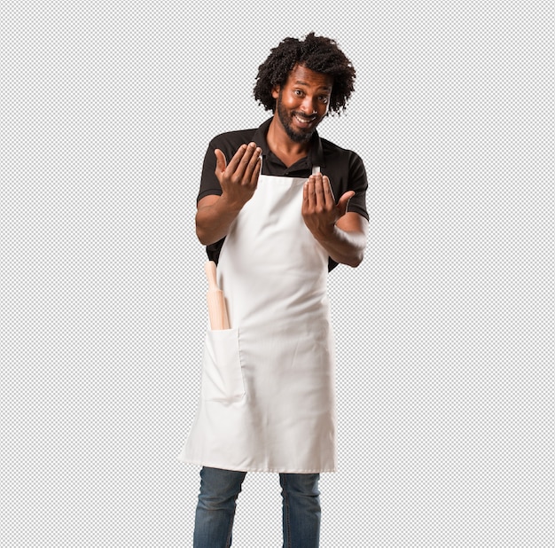 Hübscher afroamerikanerbäcker, der einlädt zu kommen, zuversichtlich und lächelnd, eine geste mit der hand machend, positiv und freundlich seiend Premium PSD