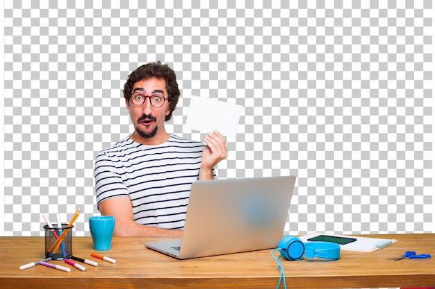Junger verrückter grafikdesigner auf einem schreibtisch mit einem laptop und mit einem plakat Premium PSD