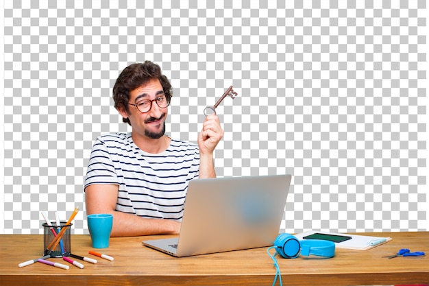 Junger verrückter grafikdesigner auf einem schreibtisch mit einem laptop und mit einem weinleseschlüssel Premium PSD