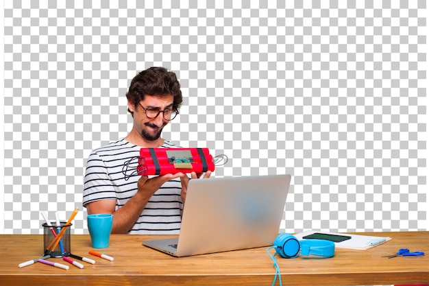 Junger verrückter grafikdesigner auf einem schreibtisch mit einem laptop und mit einer dynamitbombe Premium PSD