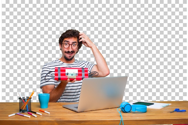 Junger verrückter grafikdesigner auf einem schreibtisch mit einem laptop und mit einer dynamitbombe Premium PSD