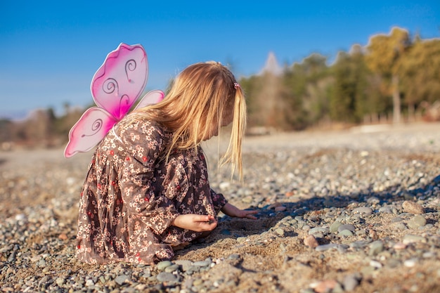 Adorable petite fille jouant sur la plage en une journée ensoleillée d'hiver Photo Premium