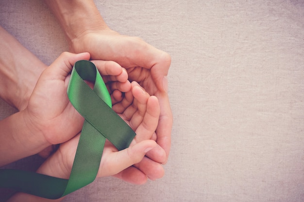 Adulte et enfant tenant un ruban vert, sensibilisation au cancer Photo Premium