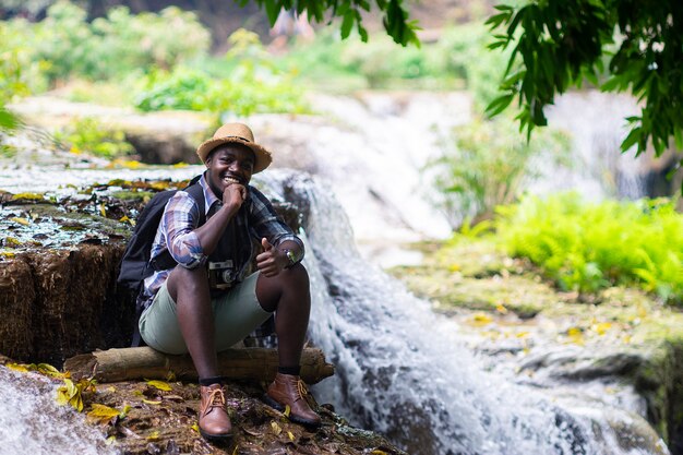 African man traveler relaxant la liberté à la cascade Photo Premium