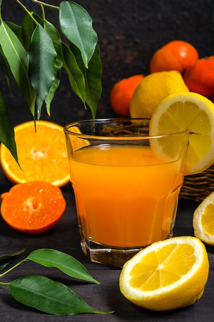 Agrumes orange citron dans un panier et jus sur un fond sombre Photo Premium