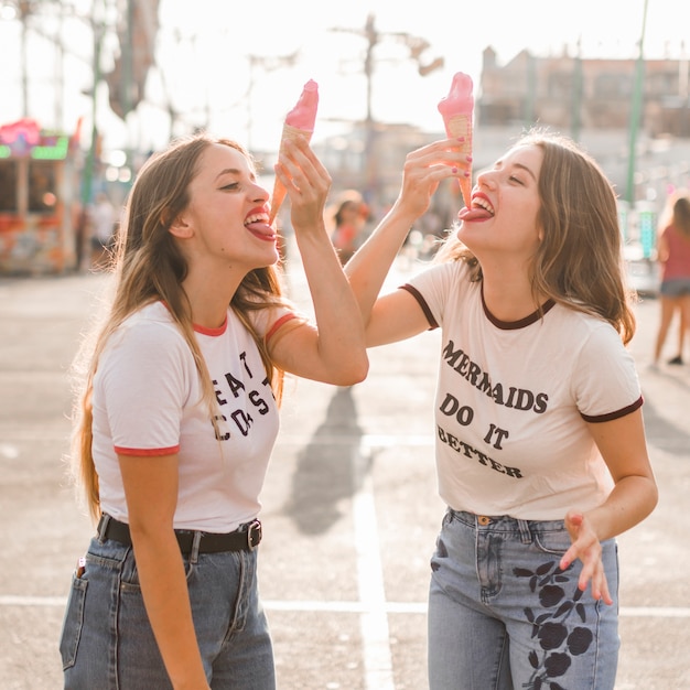 Amis mangeant une glace dans le parc d'attractions Photo gratuit