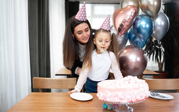 Anniversaire Maman Et Fille En Chapeaux Celebrent Sur La Table Un Gateau Et Des Ballons De Fete Photo Premium