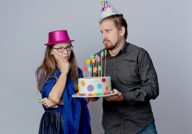 Anxieux Bel Homme En Chapeau D Anniversaire Tenant Le Gateau Et Regardant La Jeune Fille Agacee Avec Des Lunettes Portant Un Chapeau Rose Tient Le Sifflet Et Met La Main Sur Le Menton