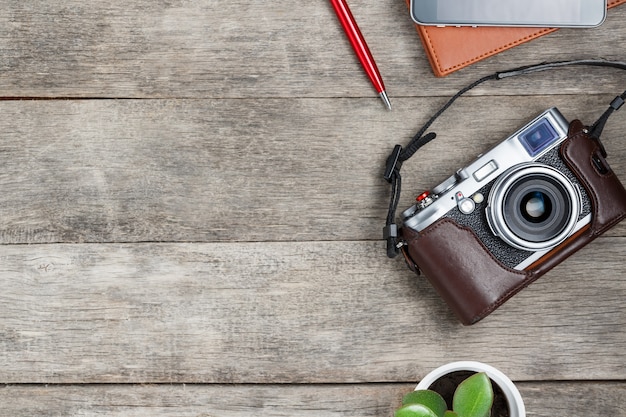 Appareil photo classique, avec un bloc-notes marron, un stylo rouge, un téléphone et une croissance verte. liste de concept pour un photographe de voyage Photo Premium