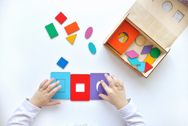 Apprendre les couleurs et les formes. l'enfant récupère une trieuse. jouets logiques éducatifs pour enfants. gros plan des mains des enfants. jeux montessori Photo Premium