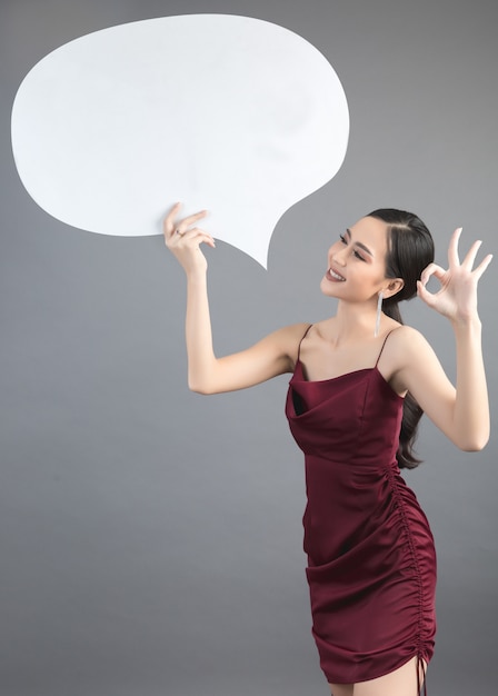 Asiatique femme tenant et levant à bulle de dialogue avec un espace vide pour le texte Photo gratuit
