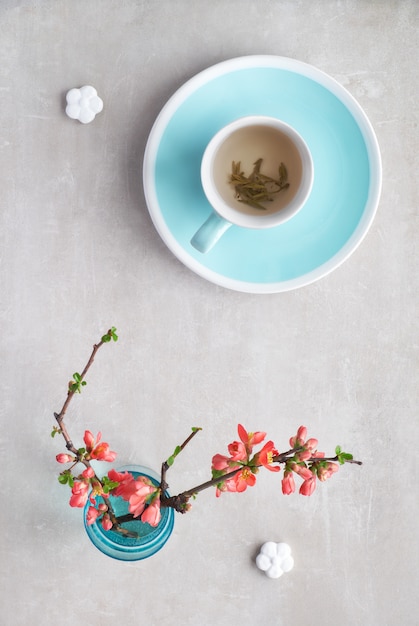 Au Printemps étendez Une Tasse De Thé Vert Et De Fleurs De Coings Japonais Sur Une Pierre Grise 9939