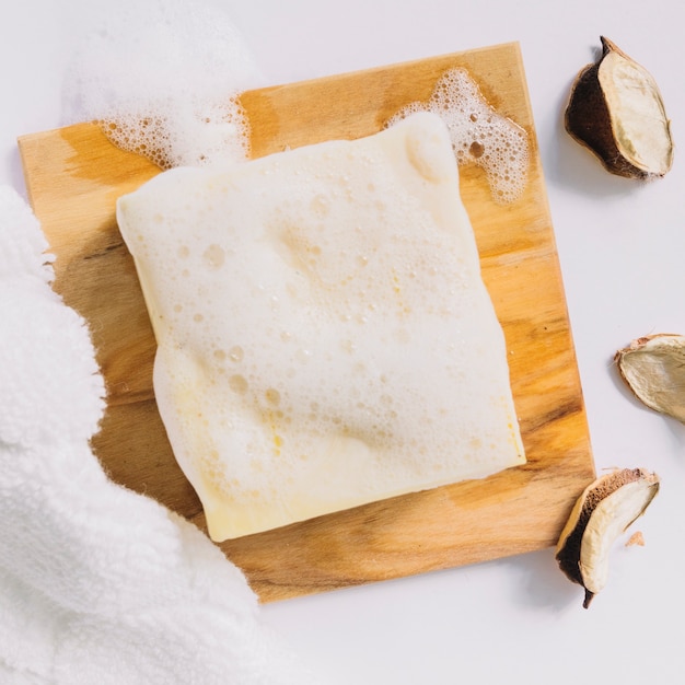 Barre de savon avec de la mousse sur une planche de bois à ...