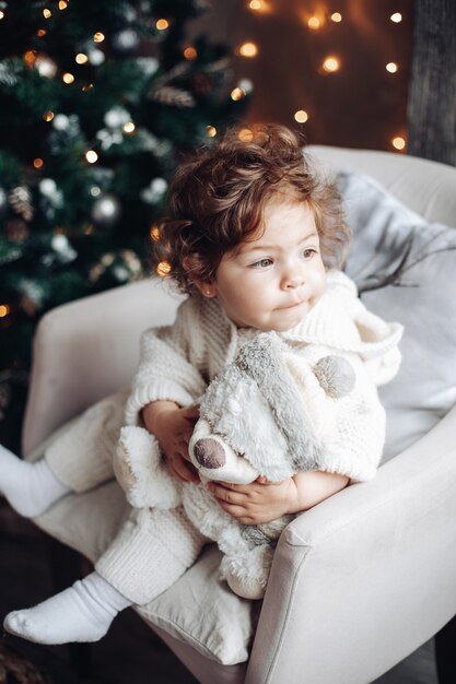 Beau Bebe Aux Cheveux Boucles En Blanc Assis Dans Une Chaise Avec Ours En Peluche Photo Gratuite