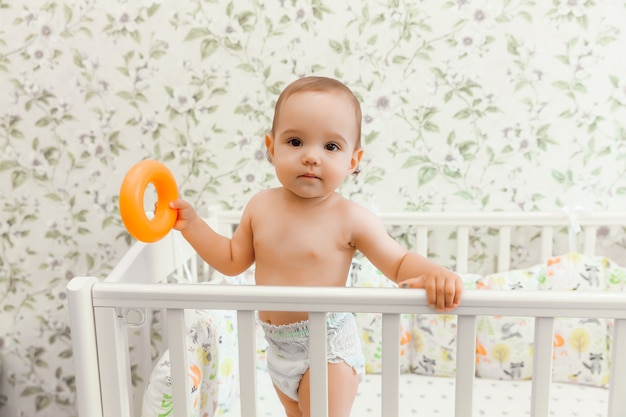 Un Bebe De 11 Mois Dans Une Couche Se Tient Dans Son Lit D Enfant Dans Le Lit Photo Premium