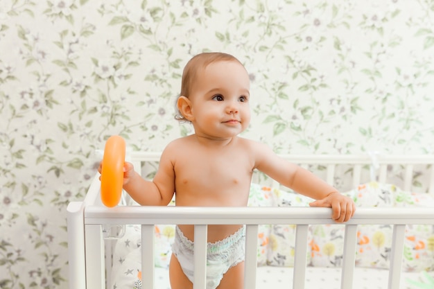 Un Bebe De 11 Mois Dans Une Couche Se Tient Dans Son Lit D Enfant Dans Le Lit Photo Premium