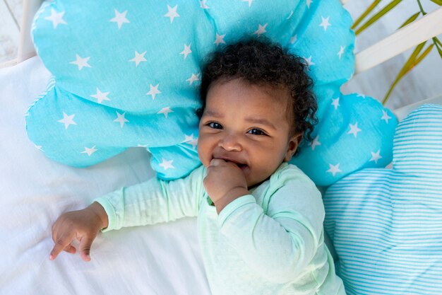 Un Bebe Africain Qui Rit Est Allonge Sur Le Dos Sur Un Lit A La Maison Sur Un Lit En Coton Bleu Et Sourit Photo Premium