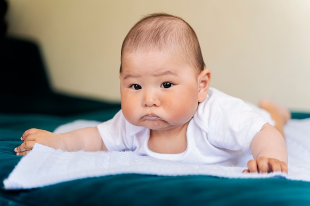 Un Bebe Asiatique Nouveau Ne Pour La Publicite Est Couche Sur Le Ventre Sur Le Lit Visage Insatisfait Photo Premium