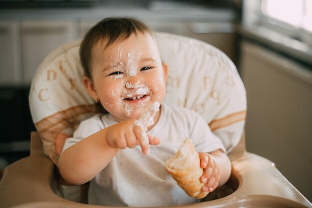 Bebe Dans La Cuisine Mange Avec Impatience Les Delicieuses Cornes De Creme Fourrees D Une Creme A La Vanille Tres Rigolote Photo Premium