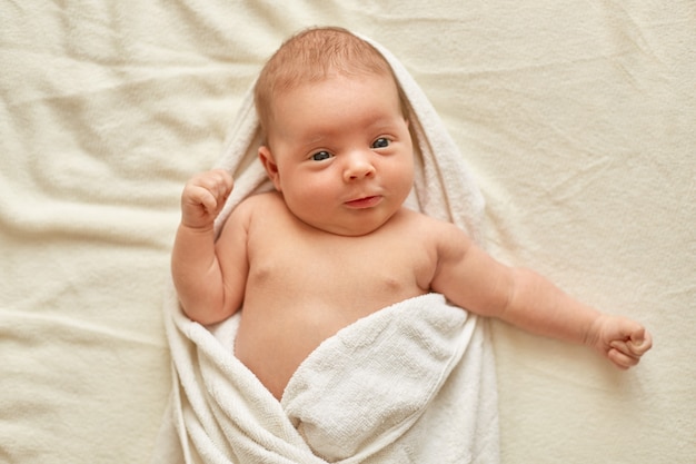 Bebe Enfant Apres Le Bain Allonge Sur Le Lit Sur Une Couverture Blanche Regardant La Camera Etant Enveloppe Dans Une Serviette Bebe Apres La Douche Charmant Enfant Nouveau Ne Photo Gratuite