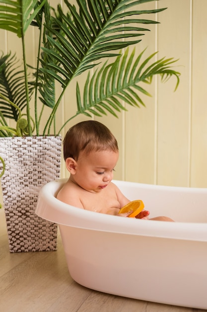 Bebe Garcon Assis Dans Une Baignoire Avec Des Oranges Sur Un Mur En Bois Photo Premium