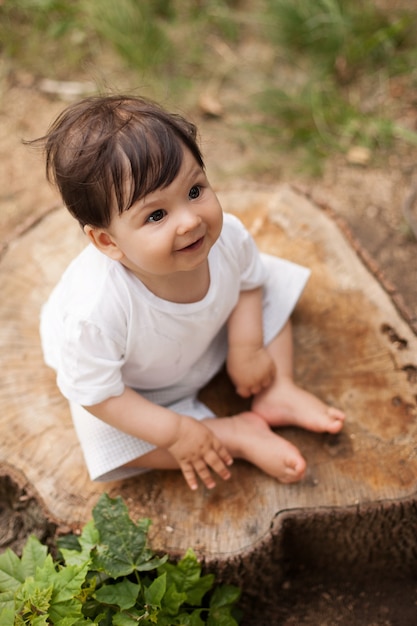 Bebe Garcon En Blanc T Short Assis Sur Une Souche D Arbre Dans Le Parc Photo Premium