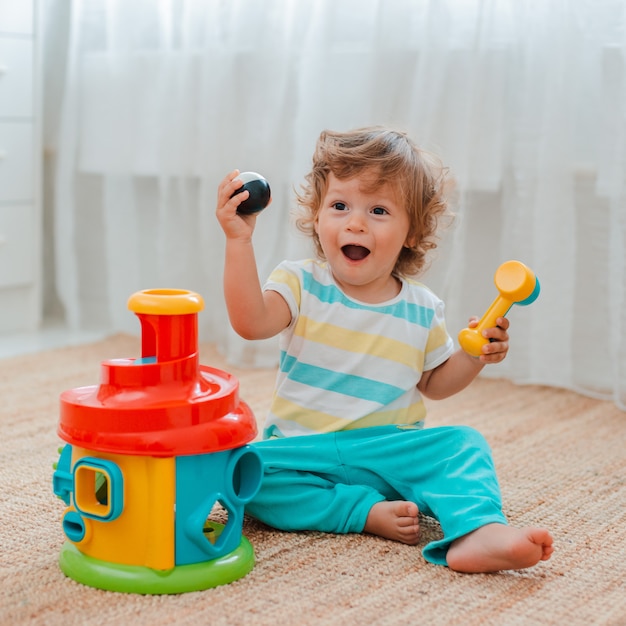 Bebe Joue Par Terre Dans La Piece Avec Des Jouets En Plastique Educatifs Photo Premium