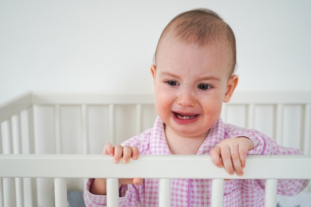 Bebe En Magnifique Pyjama A Carreaux Roses L Enfant S Est Reveille Et A Beaucoup Pleure Un Enfant Est Debout Dans Son Berceau Blanc Photo Premium