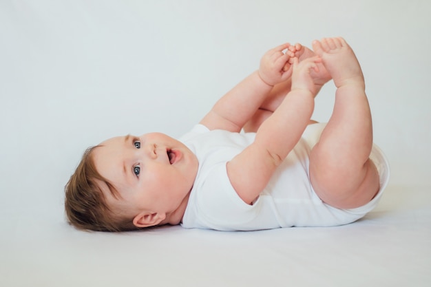 Bebe Nourrisson Souriant Allonge Sur Le Dos Et Atteignant Les Pieds Sur Blanc Photo Premium