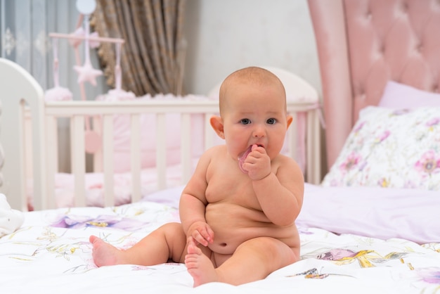 Un Bebe Nu Mignon Et Potele Regardant La Camera Dans Une Chambre D Enfant Rose Avec Berceau Photo Premium