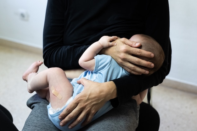 Bebe Pleure Apres La Vaccination Avec Du Pansement Ou Du Platre A La Cuisse Reconforte Par Sa Mere Qui L Allaite Photo Premium