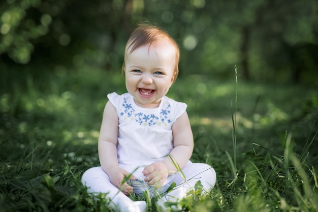 Le Bebe S Assoit Sur L Herbe Verte Du Parc Et Rit Les Deux Premieres Dents Du Bebe Photo Premium