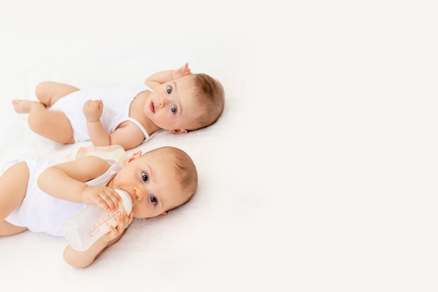 Bebes Jumeaux Garcon Et Fille Avec Une Bouteille De Lait Sur Un Lit Blanc Photo Premium