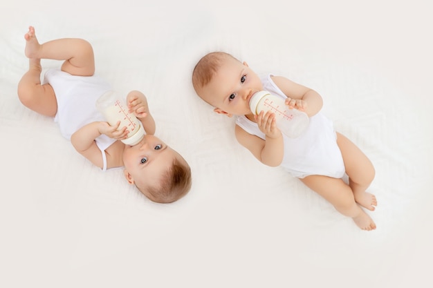 Bebes Jumeaux Garcon Et Fille Avec Une Bouteille De Lait Sur Un Lit Blanc Photo Premium