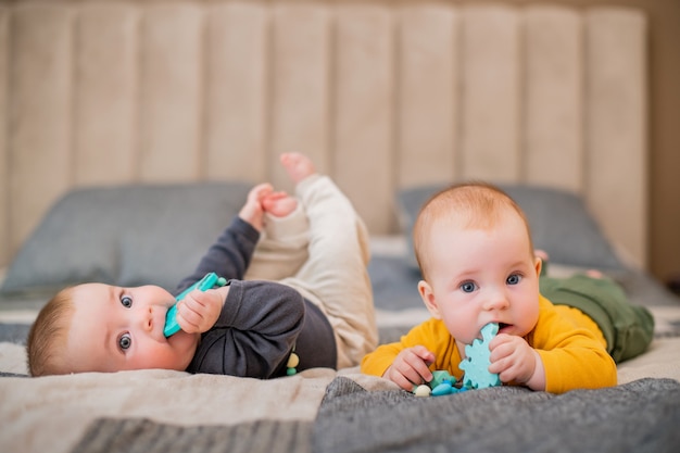 Les Bebes Jumeaux Se Trouvent Sur Le Lit Et Rongent Les Dents Photo Premium