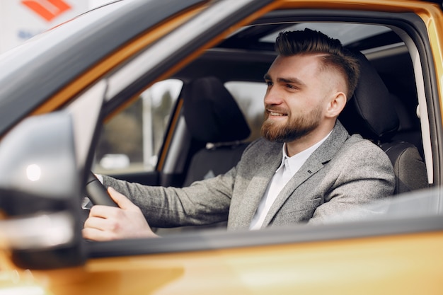 Bel homme élégant dans un salon de l'automobile Photo gratuit