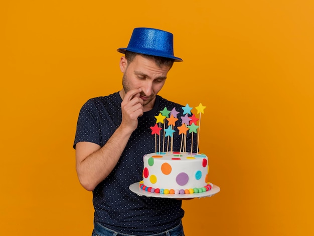 Bel Homme Malheureux Portant Un Chapeau De Fete Bleu Tient Et Regarde Le Gateau D Anniversaire Isole Sur Un Mur Orange Avec Espace De Copie Photo Gratuite