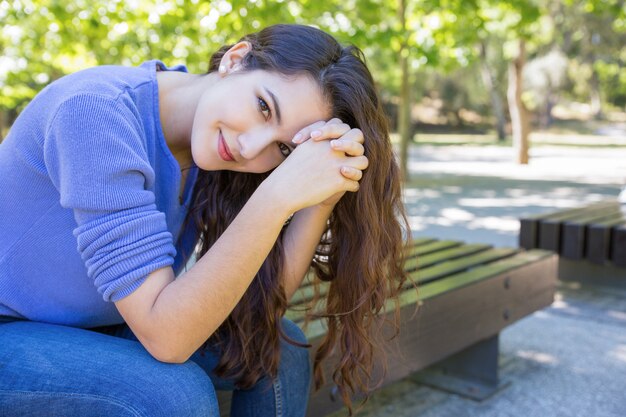 Belle femme avec des cheveux en bonne santé, assis sur un banc dans le parc Photo gratuit