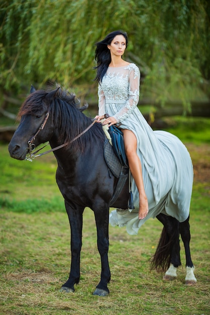 Belle Femme En Robe Avec Un Cheval  Noir Dans La Nature 