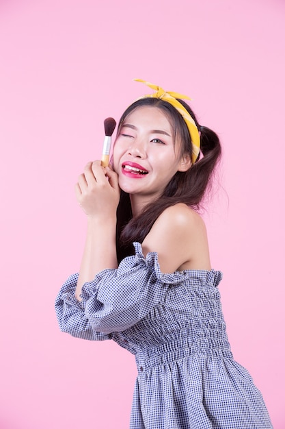 Belle femme tenant un pinceau, brossé sur un fond rose. Photo gratuit