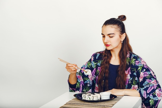 Belle fille mangeant un sushi en studio Photo gratuit