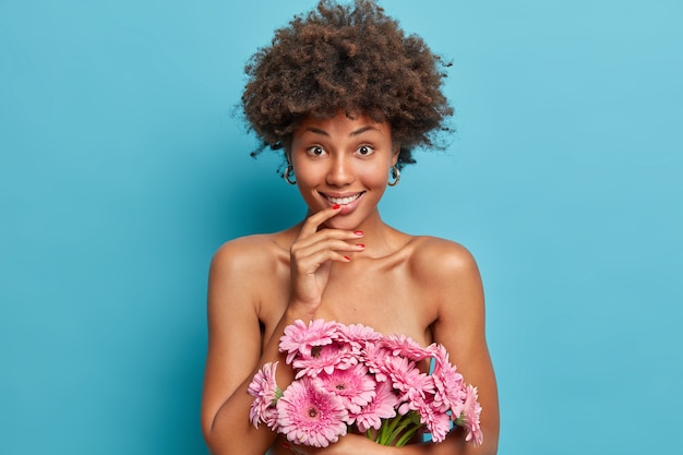 Belle Jeune Femme Nue Avec Une Coiffure Afro Tient Un Joli Bouquet De Gerberas, A Une Peau Saine Bien Soignée, Des Poses Photo gratuit