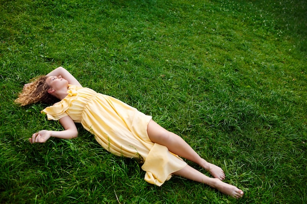 belle jeune fille en robe jaune allongée sur l herbe photo gratuite