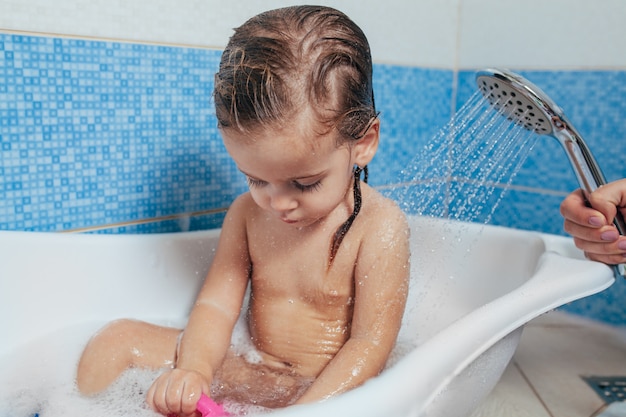 Belle Petite Fille Prenant Un Bain A La Maison Un Joli Bebe Est Assis Dans La Salle De Bain Et Joue Avec Des Jouets Et De L Eau Photo Premium