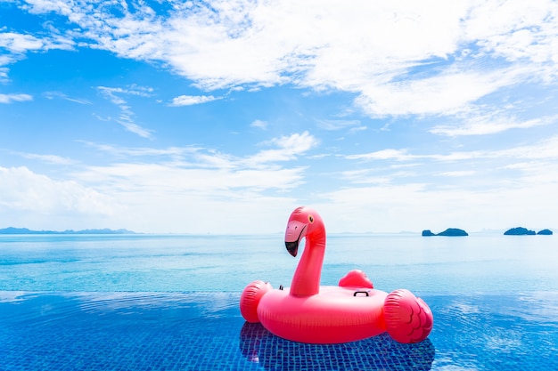 Belle piscine extérieure dans un complexe hôtelier avec flamant rose flottant autour d'un nuage blanc de mer, océan, sur ciel bleu Photo gratuit