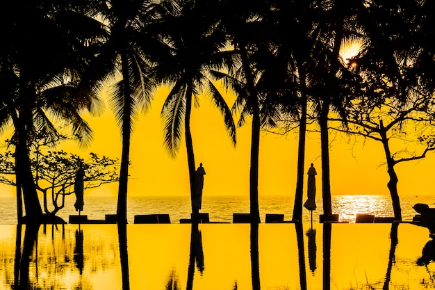 Belle silhouette cocotier sur le ciel autour de la piscine dans l'hôtel resort près de la mer océan b Photo gratuit