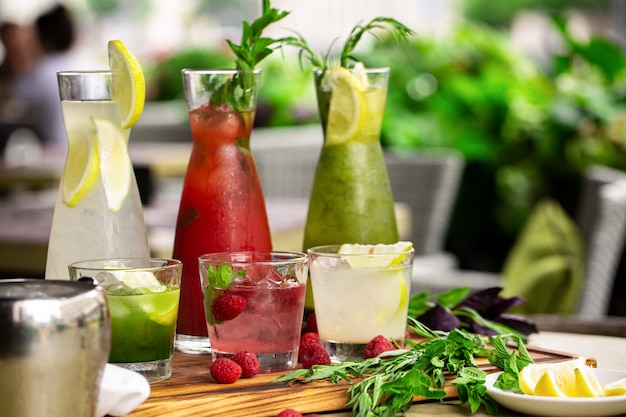 Boissons non alcoolisées estivales, un ensemble de limonades. des limonades dans des pichets sur la table, autour desquelles sont disposés les ingrédients. Photo Premium